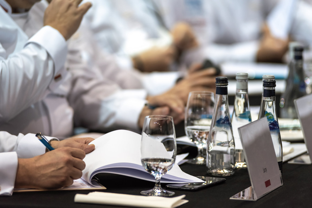 Chefs en veste blanche réunis autour d'une table, dossiers en main