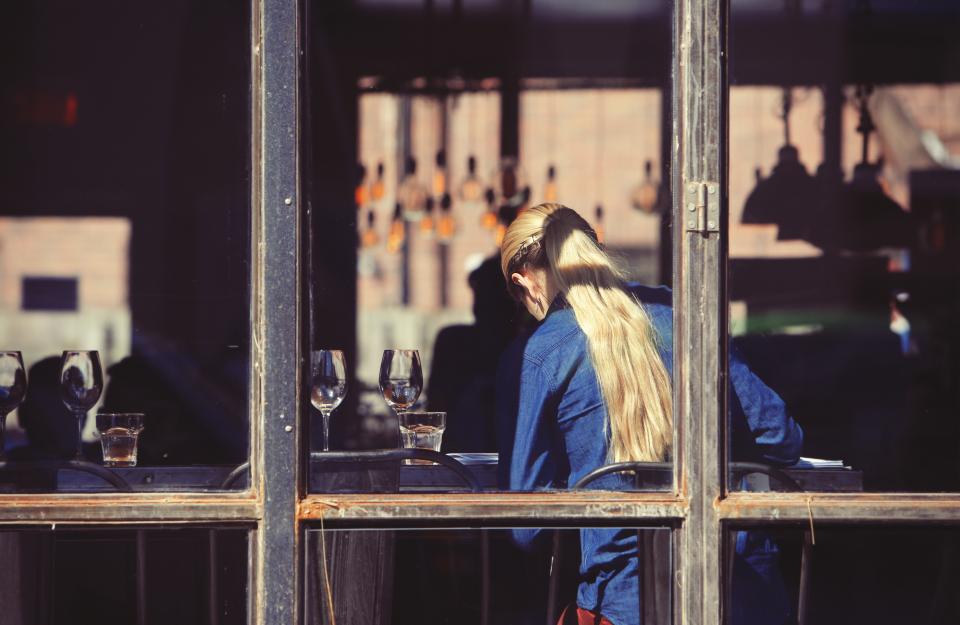 Recrutement digital en restauration Serveuse de dos dans une salle de restaurant, vue à travers une vitre
