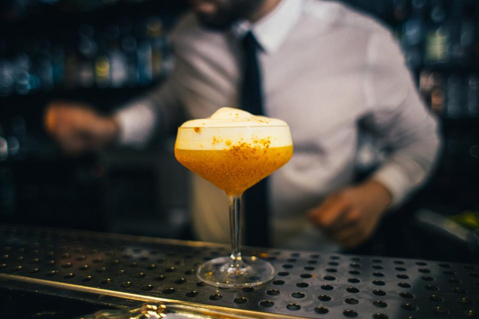 Barman préparant un cocktail derrière le comptoir d'un bar