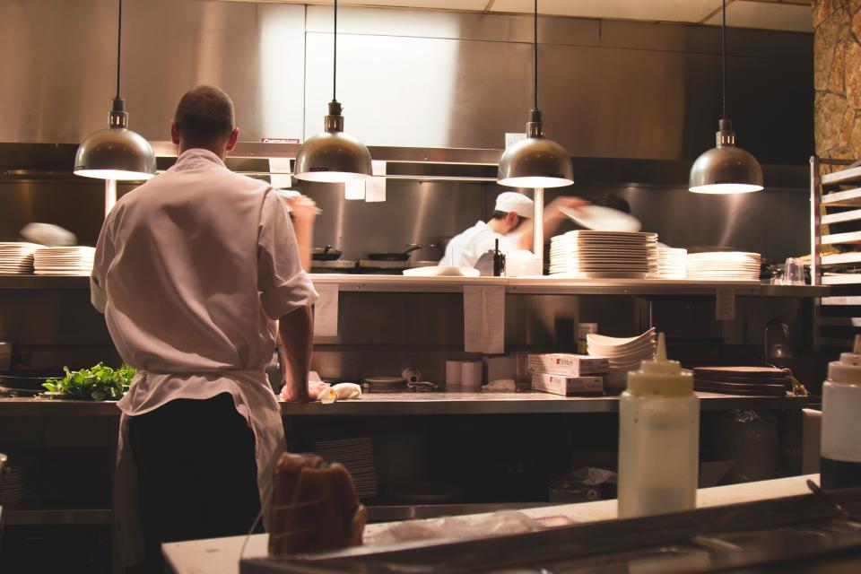 Cuisine professionnelle en pleine activité avec deux cuisiniers au passe