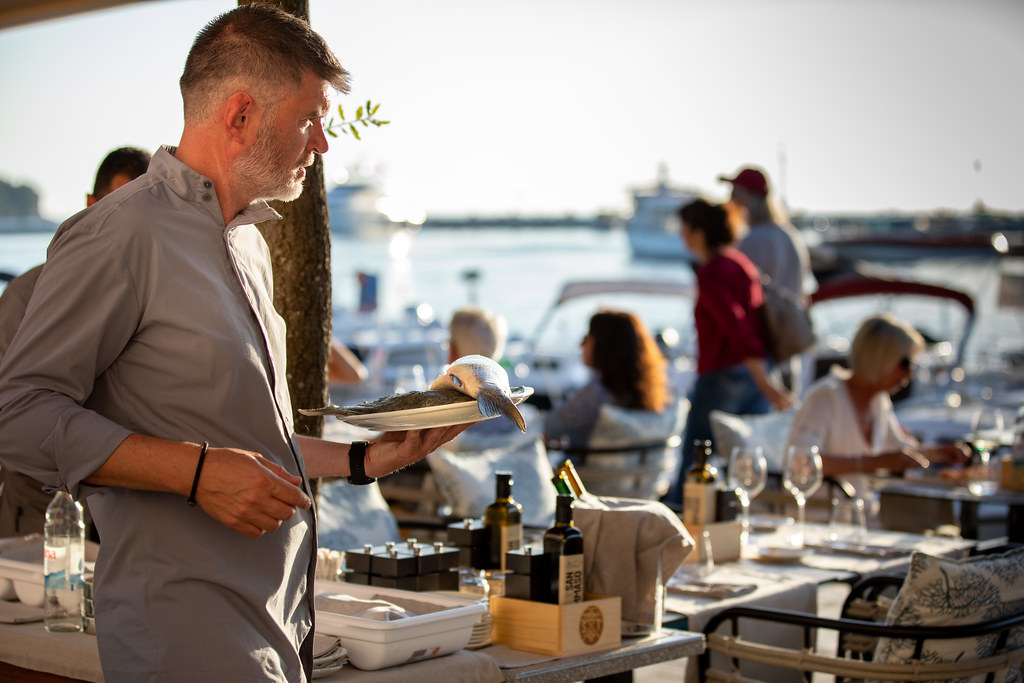 Serveur en terrasse portant une assiette pendant le service d'un restaurant