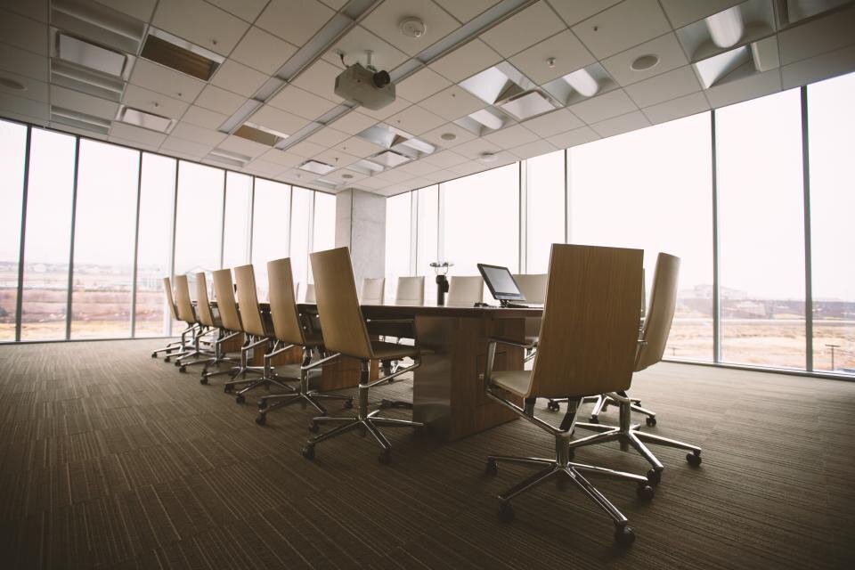 Grande salle de réunion vide avec une longue table et des fauteuils de bureau