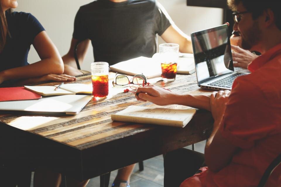 Petite équipe réunie autour d'une table de travail avec ordinateurs et carnets
