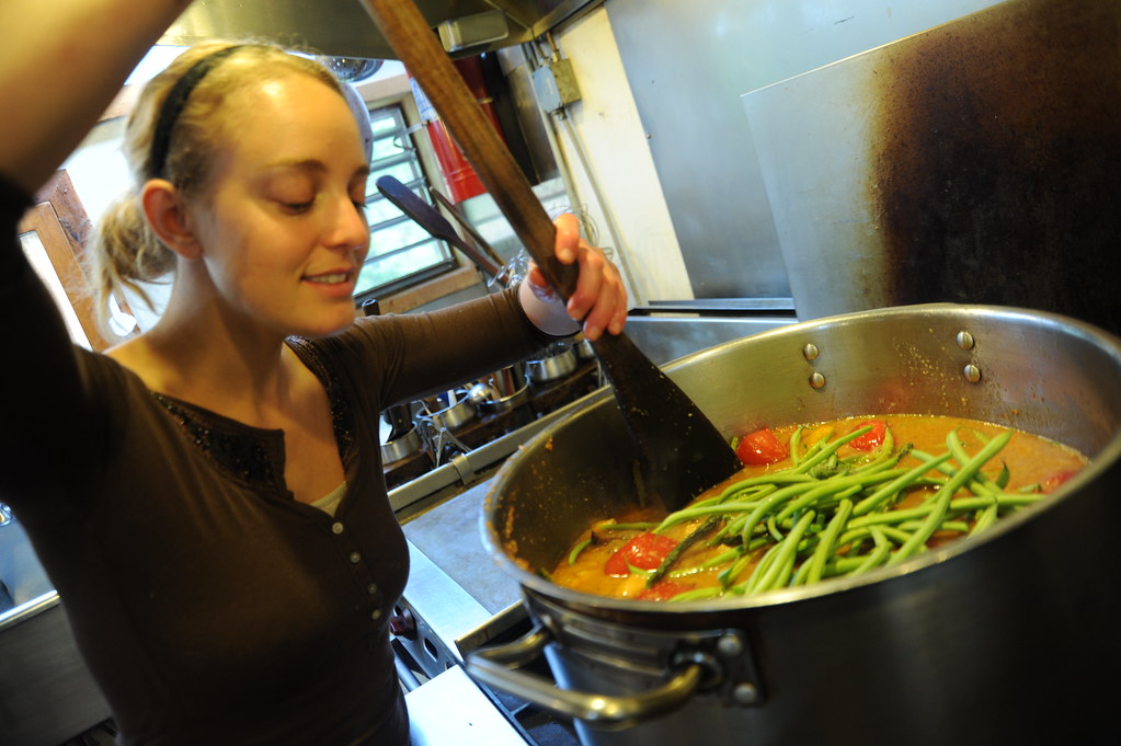 Cuisinier souriant en train de préparer un plat dans une cuisine professionnelle