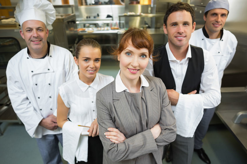 Manager d'établissement entourée de son équipe de cuisine et de salle